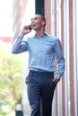 Happy young businessman walking and talking on mobile phone Royalty Free Stock Photo