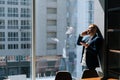 Happy young businessman wearing fashion suit is talking on mobile phone in modern office room Royalty Free Stock Photo