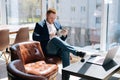 Happy young businessman wearing fashion suit is using mobile phone in modern office room Royalty Free Stock Photo