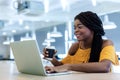 Happy young businesswoman African American cheerful demeanor raise holding coffee cup smiling looking laptop screen. Royalty Free Stock Photo