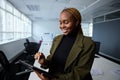 Happy young businesswoman in businesswear using digital tablet and digitized pen by desk in office