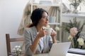 Happy young businesswoman drink coffee dreaming in home office