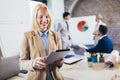 Young businesswoman holding digital tablet with team discussing project in the background Royalty Free Stock Photo