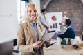 Young businesswoman holding digital tablet with team discussing project in the background Royalty Free Stock Photo