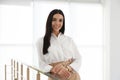 Happy young businesswoman leaning on railing in office Royalty Free Stock Photo