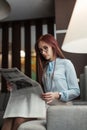 Happy young businesswoman reading newspaper in hotel lobby Royalty Free Stock Photo