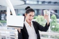 happy young businesswoman is showing money and laptop with blank copy space screen and clipping path in urban city. girl holding Royalty Free Stock Photo