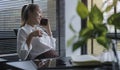 Happy young businesswoman sitting at her office desk and talking on mobile phone Royalty Free Stock Photo