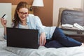 Happy young businesswoman using tablet pc in hotel room. Online shopping with credit card. Royalty Free Stock Photo