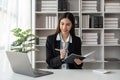 Happy young businesswoman working on laptop and taking notes in office Royalty Free Stock Photo