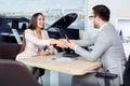 Happy car dealer and customer shake hands after successfully signed contract. Royalty Free Stock Photo