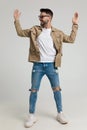 Happy young casual guy in jacket looking to side and holding hands up Royalty Free Stock Photo