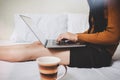 Happy young casual woman working or shopping online or WFH work from home on laptop while sitting in bed Royalty Free Stock Photo