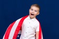 Happy young caucasian american boy kid child schoolboy wraps himself in a U.S. flag and look at camera Royalty Free Stock Photo