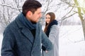 Happy young caucasian couple holding hands and looking at each other, smiling cute, while walking in winter forest Royalty Free Stock Photo