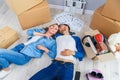 Happy young caucasian couple lying down on the wooden floor while having a break while moving to new house. Top view. Royalty Free Stock Photo