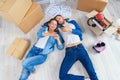 Happy young caucasian couple lying down on the wooden floor and messaging at smart phones during having break while Royalty Free Stock Photo