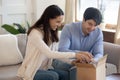 Happy young couple unbox cardboard box with online order