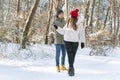 Happy young caucasian couple is walking in snow-covered park. Lovers enjoy sunny winter forest Royalty Free Stock Photo