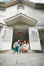 Happy young caucasian family of four sitting at their front door smiling and looking at the camera. Two parents sitting Royalty Free Stock Photo