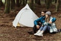 Happy young caucasian family in jackets sitting, relaxing near tent, enjoy adventure, free time Royalty Free Stock Photo