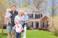 Happy Young Caucasian Family Outside In Front of Their New Home