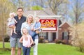 Happy Young Caucasian Family Outside In Front of Their New Home and Sold Real Estate Sign Royalty Free Stock Photo