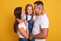 Happy young Caucasian family in photo studio. Father, mother and charming daughter. Parents hugging little adorable girl dressed Royalty Free Stock Photo