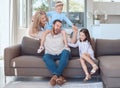 Happy young caucasian family sitting on a sofa in the living room at home and playing. Adorable little girls and their Royalty Free Stock Photo