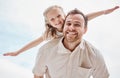 Happy young caucasian father giving his daughter a piggyback ride while holding her arms outstretched and having fun on Royalty Free Stock Photo