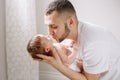 Happy young Caucasian father kissing newborn baby. Dad man parent holding rocking child daughter son on hands. Authentic lifestyle Royalty Free Stock Photo