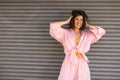 Happy young caucasian girl looks at camera with hair mussed up standing on grey wall background. Royalty Free Stock Photo