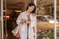 Happy young caucasian girl with shopping bag stands in doorway of store. Royalty Free Stock Photo