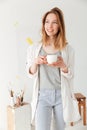 Happy young caucasian lady painter drinking coffee. Royalty Free Stock Photo