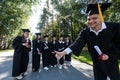 Happy young caucasian male graduate showing thumbs up. A group of graduate students outdoors. Royalty Free Stock Photo