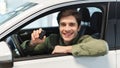 Happy young Caucasian man showing key from auto, sitting inside car salon, buying brand new automobile at dealership Royalty Free Stock Photo