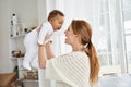 Happy caucasian mother having fun lifting cute little baby daughter.