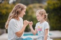 Happy young caucasian mother sitting with her adorable little daughter in the garden at home and making pinky promises