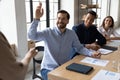 Smiling male employee raise hand at team meeting Royalty Free Stock Photo