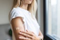Happy young caucasian woman with blonde hair in white t-shirt showing patch on arm, feeling good after anti coronavirus Royalty Free Stock Photo