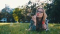 Happy young caucasian woman blowing soap bubbles while lying in the grass in the park Royalty Free Stock Photo