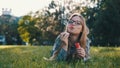 Happy young caucasian woman blowing soap bubbles while lying in the grass in the park Royalty Free Stock Photo