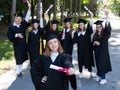 Happy young caucasian woman celebrating graduation with classmates. A group of graduate students outdoors. Royalty Free Stock Photo