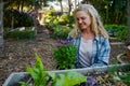 Happy young caucasian woman in checked shirt holding flowers in plant nursery Royalty Free Stock Photo