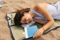 Happy young caucasian woman lying on underlay and reading book on beach in sunny weather. Royalty Free Stock Photo