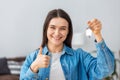 Happy young caucasian woman owner of new house shows the key to a new home, looking at the camera and smiling Royalty Free Stock Photo