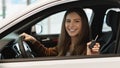 Happy young Caucasian woman showing key from auto, sitting inside car salon, buying new automobile at dealership, banner Royalty Free Stock Photo