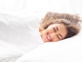 Happy Young Caucasian woman smiling and sleeping in bed with relaxation and tranquil and calm mind in white background. Royalty Free Stock Photo