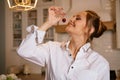 Happy young woman in a white shirt eating a sweet cherry in the kitchen Royalty Free Stock Photo