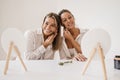 Happy young caucasian women use jade scraper while looking at mirror on white background.